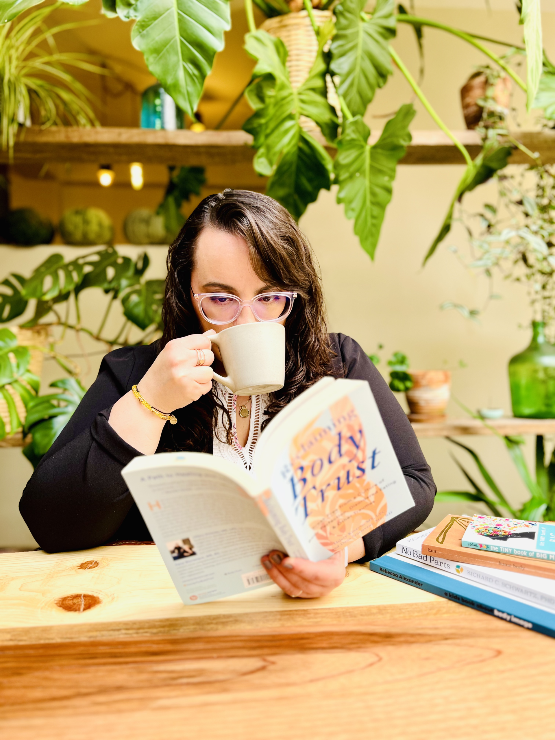 Nicole Marshall Concha reading the book “Body Trust” while drinking coffee, showing her dedication to trauma-informed and size-inclusive care.